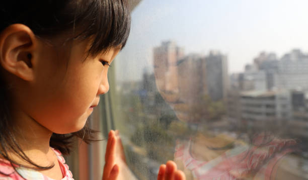 istock a Asian girl watching through glass window. 1302548343