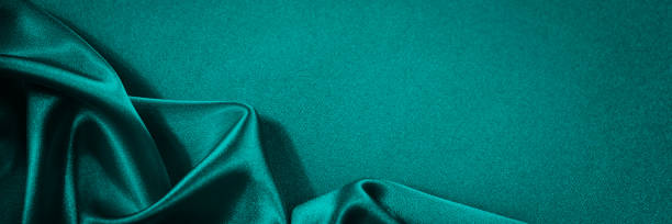 istock Blue green silk satin background. Soft wavy folds on smooth, shiny fabric. 1302549623