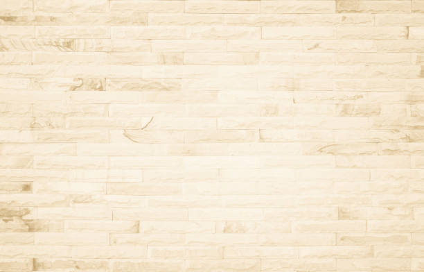 istock Empty background of wide cream brick wall texture. Beige old brown brick wall concrete or stone textured, wallpaper limestone abstract flooring/Grid uneven interior rock. Home decor design backdrop. 1302550351