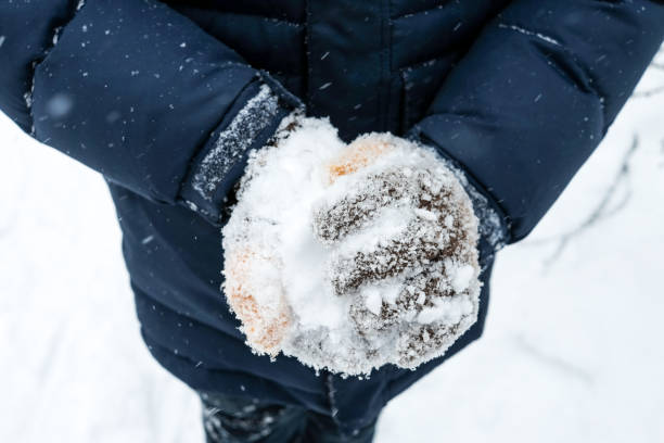 istock close up gloved hands make a snowball 1302551416