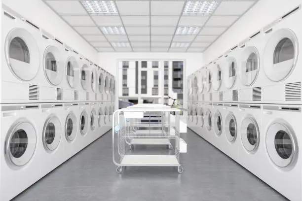 Photo of White Laundry Machines And Dryers In A Row In Laundromat With Wheeled Laundry Baskets.
