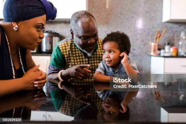 Photo libre de droit de Grandsparents Parlant Au Petit Garçon À La Table De Cuisine banque d'images et plus d'images libres de droit de Grand-mère