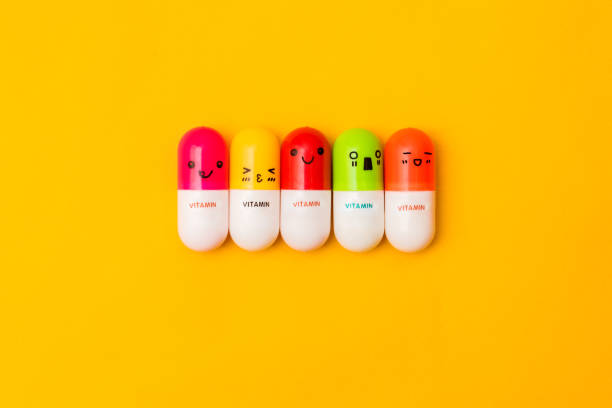 Smiling faces colorful vitamin capsules on yellow background