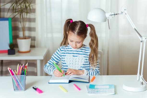 pretty child girl writing notes in notebook daily planner, planning week, working or studying at home - note pad desk office meeting imagens e fotografias de stock