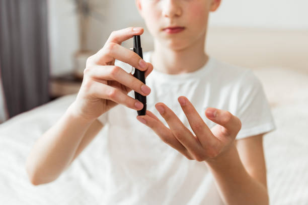 Teen boy takes a blood sample for diabetes with lancet pen. Problems of diabetes and insulin resistance in childhood Teen boy takes a blood sample for diabetes with lancet pen. Problems of diabetes and insulin resistance in childhood hyperglycemia stock pictures, royalty-free photos & images