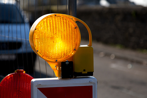 Close-up of yellow and red warning lights with street barriers at a construction site
