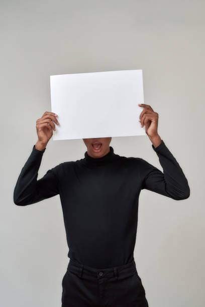 istock Young african american man hiding head behind blank poster 1302563048