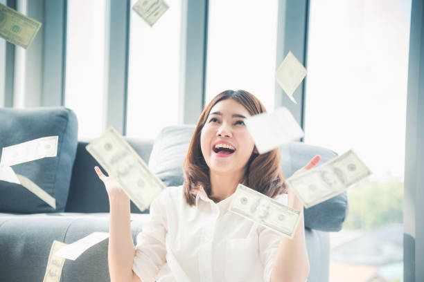 jeune femme asiatique heureuse retenant l’argent de dollar et jetez dans l’air célèbrent la chute de pluie de pluie d’argent de richesse de richesse de bonheur. gagnant femme d’affaires de succès jettent le flux de trésorerie visage heureux de  - currency wealth paper currency flying photos et images de collection