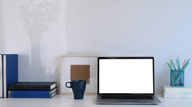 istock Simple workplace with computer laptop, coffee cup, books and stationery on white table. 1302567049