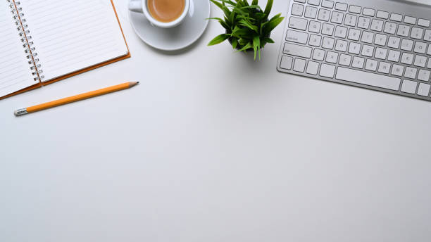 istock Top view of modern minimal workplace with coffee cup, wireless keyboard, notebook and copy space on white table. 1302567847