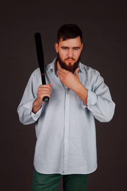 retrato de brutal, barbudo, agressivo, grande pessoa com taco de beisebol na mão no fundo escuro - bat weapon baseball mob - fotografias e filmes do acervo