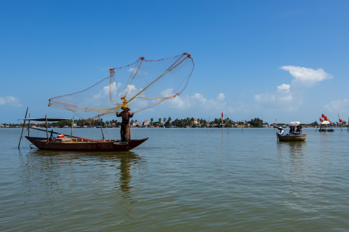 Hoi An, Quang Nam, Vietnam: Dezember 12, 2019: A traditional fisherman is throwing a fishing net at Hoi An in Vietnam