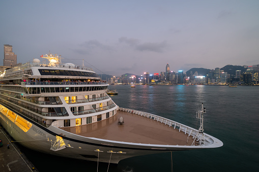 Kowloon, Hong Kong - October 8 2018: A massive cruise ship is anchored in the Tsim Sha Tsui cruise terminal across the Victoria harbor at sunset in Hong Kong