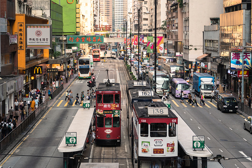 Hong Kong, China - October 27 2019: Ancient and typical double decker tramways stop at the North Point road in the crowded residential district at the east of Hong Kong island