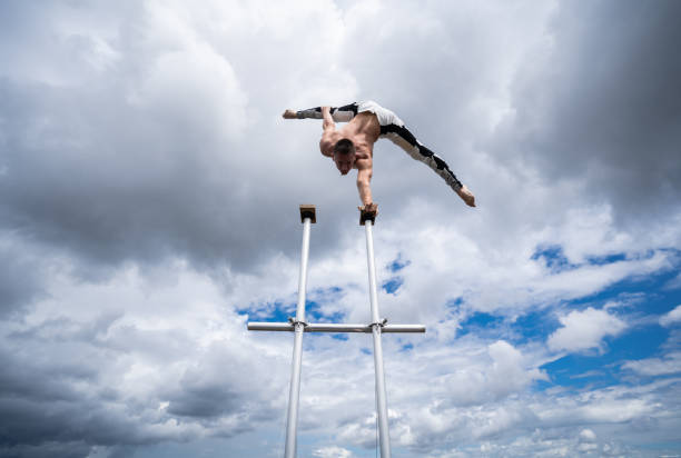 flexibler männlicher zirkus artist hält das gleichgewicht mit einer hand auf dem dach gegen erstaunliche wolkenlandschaft. motivations-, passions- und leistungskonzept - sky dramatic sky cloudscape passion stock-fotos und bilder