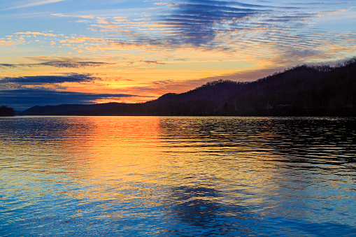 The setting sun silhouettes hills as it reflects upon the waters of the Ohio River as seen from Paden City, West Virginia.