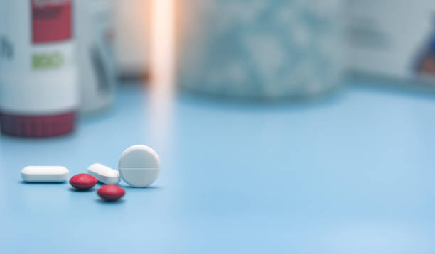Round white tablets and blurred red and white tablets pills. Pills on blurred pills plastic bottle. Healthcare and pharmaceutical industry. Pharmacy or polypharmacy concept. Prescription drugs. Round white tablets and blurred red and white tablets pills. Pills on blurred pills plastic bottle. Healthcare and pharmaceutical industry. Pharmacy or polypharmacy concept. Prescription drugs. heartburn photos stock pictures, royalty-free photos & images