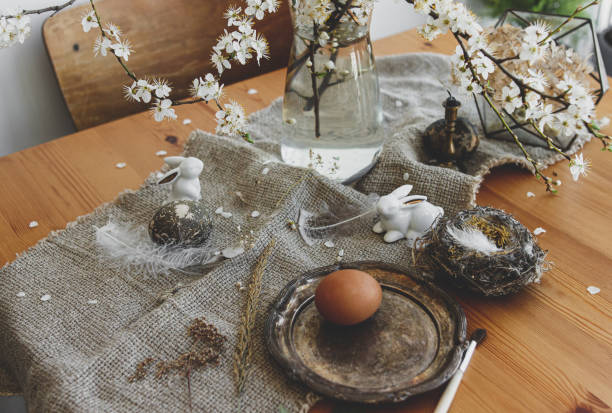 istock Natural Easter eggs, bunnies, feathers, nest and cherry blooming branch with petals on rustic linen 1302584937