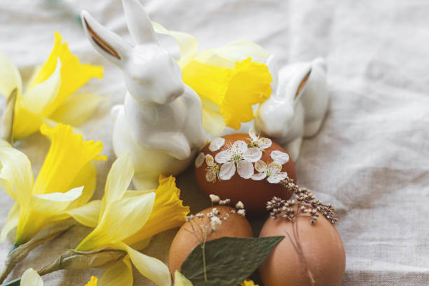 istock Happy Easter! Easter eggs decorated with dry flowers on rustic linen  with daffodils and bunnies 1302585030