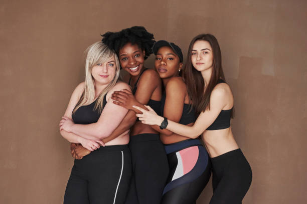 istock Closeness between different people. Group of multi ethnic women standing in the studio against brown background 1302586931