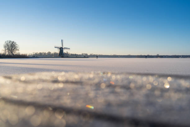 Beautiful frozen landscape featuring a calm expanse of lake with reeds in the foreground under a glowing sunset sky. Captured in Jutland, Denmark. Photo taken with a Medium Format camera and MF lens.