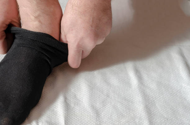 istock An adult man's hands put on new socks. 1302591985