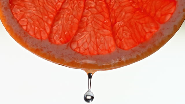 SLO MO LD Water droplet falling off a slice of grapefruit