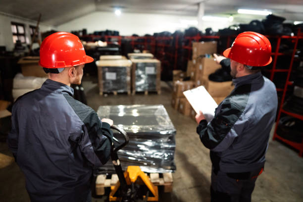 Two men, warehouse workers, sorting finished rubber mats for gym in warehouse
