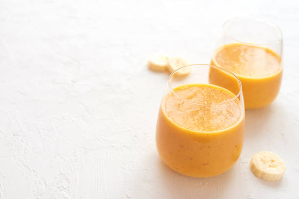 Two pumpkin banana smoothies in glasses on a white concrete background. selective focus. Copy space, healthy food concept.