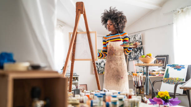 peintre afro d’art dessinant dans l’atelier, retenant la palette de couleur. - artiste photos et images de collection