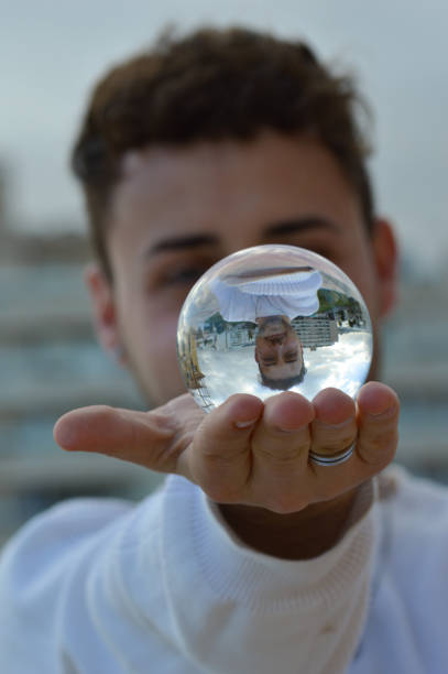 istock handsome man with a crystal ball where his reflection is seen. Selective focus 1302599970