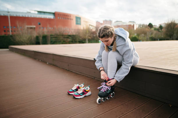 istock Young woman putting on inline roller skates 1302605306