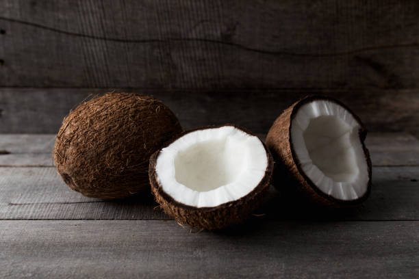 istock Broken coconuts on gray wooden background. White coconut pulp 1302605458