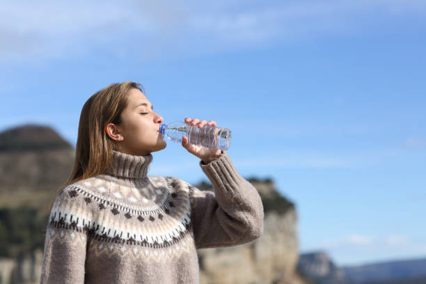 woman drinking water from bottle in winter in the mountain - water bottle water bottle drinking imagens e fotografias de stock