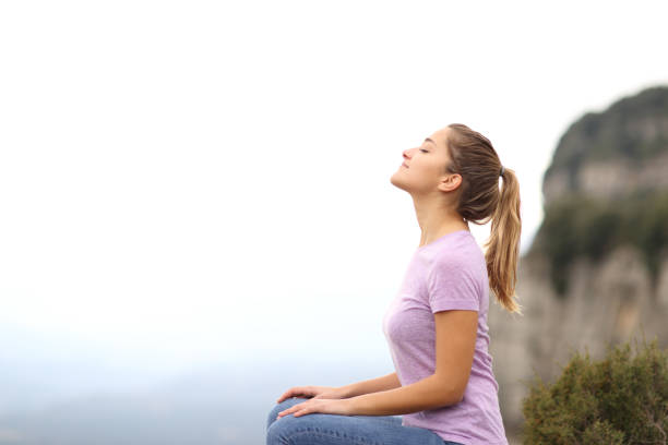 mujer sentada respirando aire fresco en la montaña - aliento fotografías e imágenes de stock