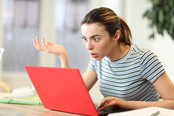 stunned student watching laptop content at home - failure relationship difficulties computer women imagens e fotografias de stock