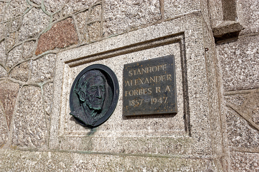 Newly Cornwall England. A memorial plaque in bronze to the master artist of the Newlyn school of painting. Two plaques one with a citation and one with his head on. Both on granite wall of local institute