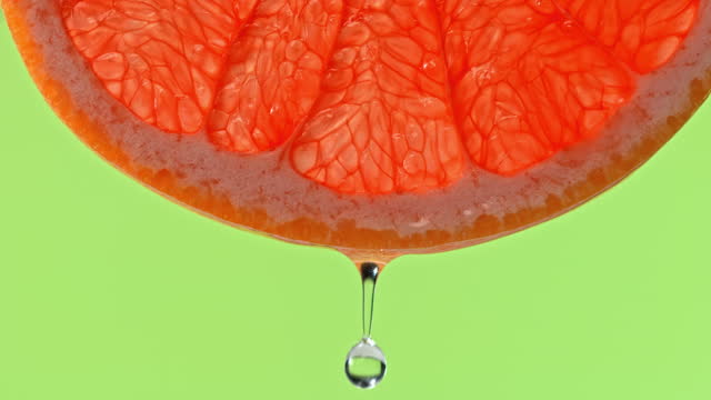 SLO MO LD Drop of water falling off a slice of grapefruit