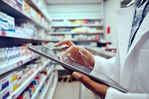 Primer plano de las manos de la joven farmacéutica revisando el inventario en una tienda médica usando una tableta digital photo