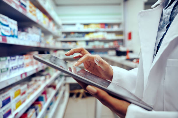 primer plano de las manos de la joven farmacéutica revisando el inventario en una tienda médica usando una tableta digital - farmacia fotografías e imágenes de stock