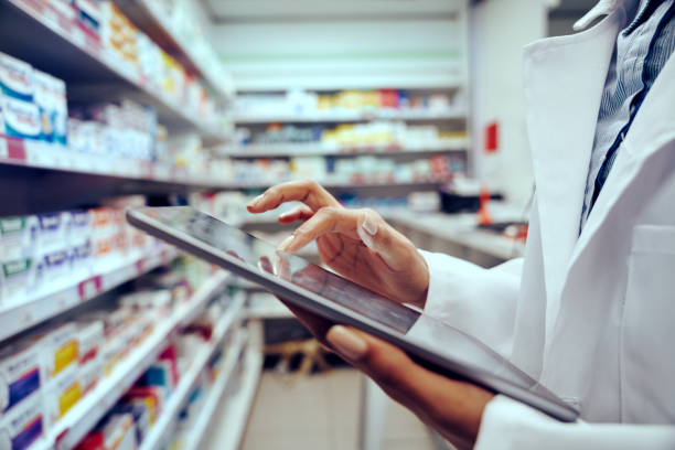 close-up das mãos de jovem farmacêutica verificando inventário em loja médica usando tablet digital - pharmacy medicine pharmacist storage room - fotografias e filmes do acervo