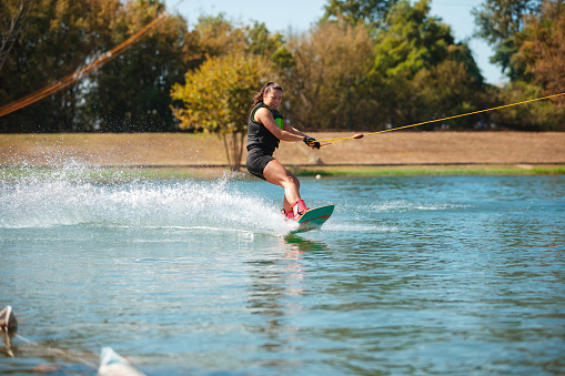 Happy handsome man wakesurfing in a lake and pulled by a boat.