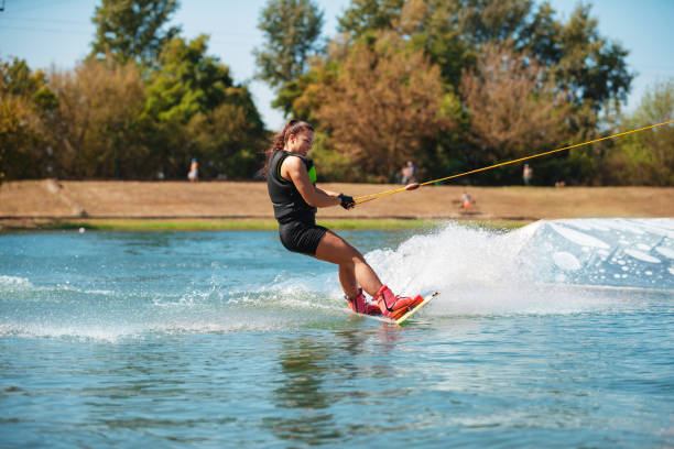 istock Young woman tilting wakeboard sidewise and spraying 1302606750