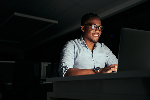 Smiling african young businessman working overtime in the office