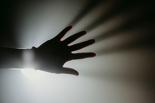 Hand of a woman reaching towards the light (spooky atmosphere, copy space).