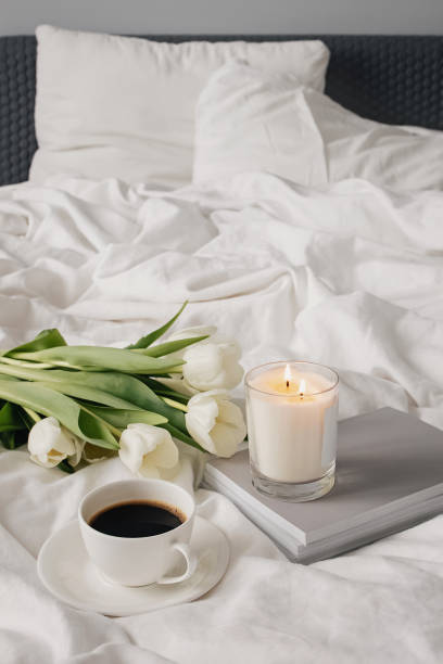 istock Coffee, candle and white tulips on bed. 1302611724