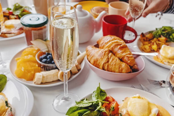 Glass of champagne close-up on the table with different breakfast and brunch dishes Glass of champagne close-up on the table with different breakfast and brunch dishes like croissants, eggs benedict, coffee and fruits. Selective focus brunch photos stock pictures, royalty-free photos & images