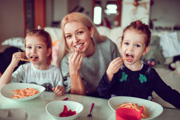 French Fries And Ketchup For Mother And Cute Female Children nch Fries And Ketchup For Mother And Cute Female Children family eating potato chips stock pictures, royalty-free photos & images