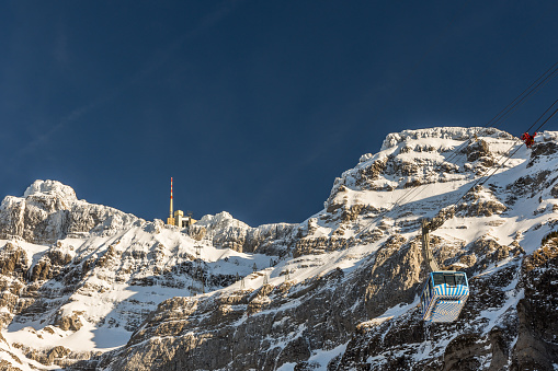 Schwaegalp, Switzerland - February 253 2019. A cable car is travelling to the summit station of mount Saentis. Winter landscape with clear blue sky. Located in the Alpstein region of northeastern Switzerland the Saentis is a landmark of the Appenzell Alps. At 2,501.9 meters above sea level, Säntis is the highest mountain in the Alpstein massif.