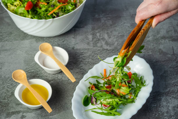istock Woman's hand serving green and healthy salad plate 1302614635
